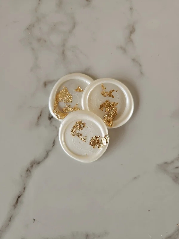 Drie handgemaakte parelmoerkleurige waxzegels met goudvlokken